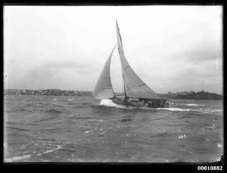 Gaff-rigged raised-deck yacht sailing on Sydney Harbour on stormy day with Garden Island in the background