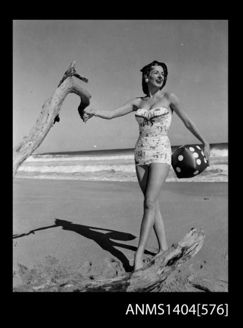 Photographic negative of a swimsuit model posing on a beach holding a blow-up dice