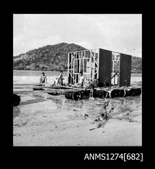 Several men constructing a lab in the water on Packe Island