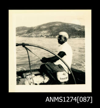 A man sitting in a boat, holding onto a rope, on Packe Island