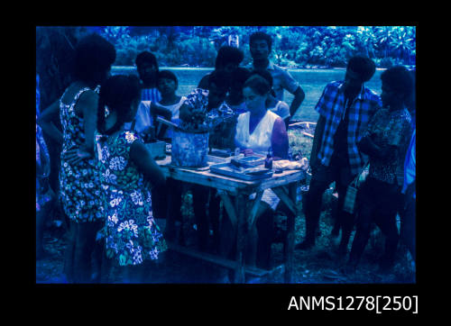 35mm colour transparency of numerous people standing around a table