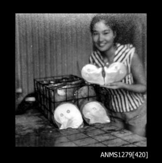 Yurie (or Yulie) George standing next to a pearl cage, holding two pearl shells