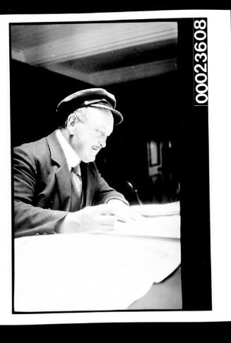 Ships and steamer crews, man seated at table looking a plans