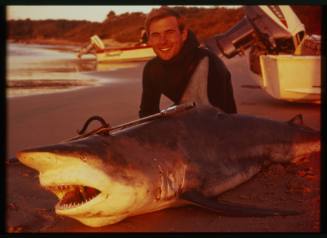 Shot of person kneeling with a caught Spinner Shark with spear rod leaning against it