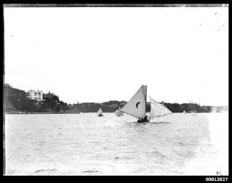 14-footer with a crescent moon emblem on the mainsail sailing past Point Piper, Sydney Harbour