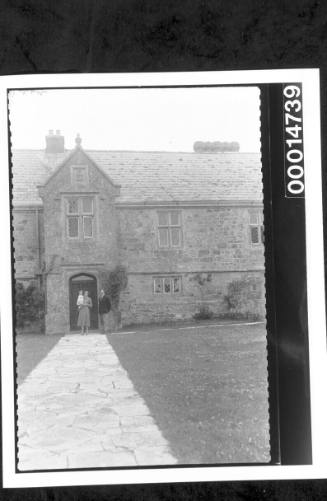 A couple and child stand outside a large stone building, England